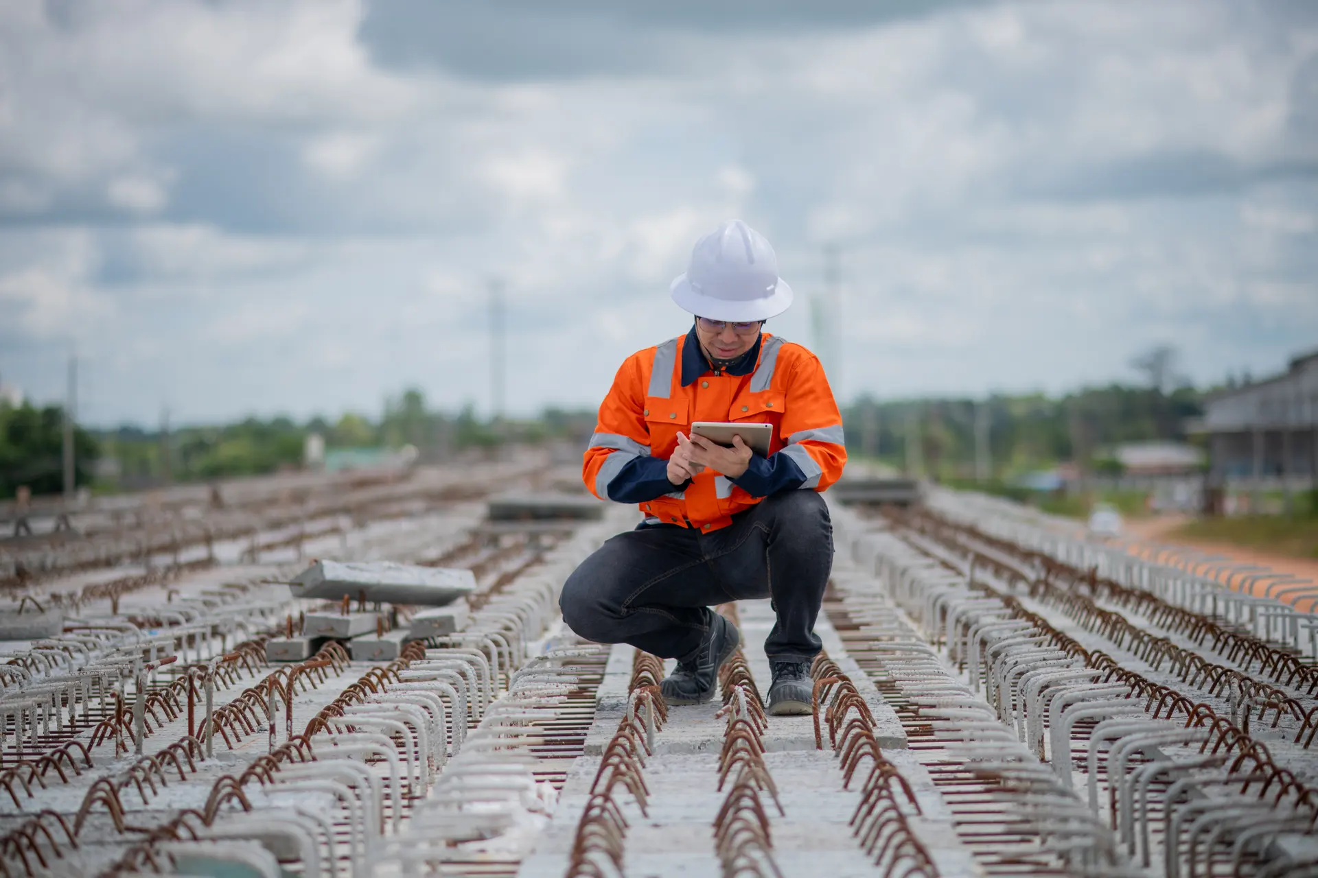 An engineer with a tablet inspecting reinforcing steel on a site
