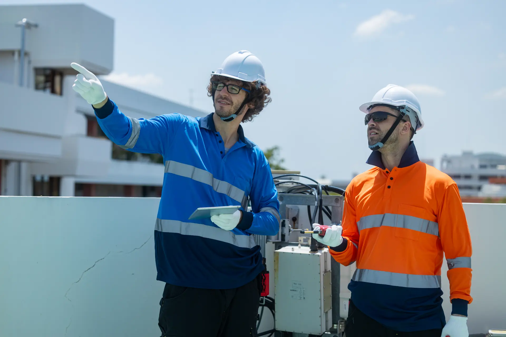 Two engineers inspecting electrical equipment on a rooftop